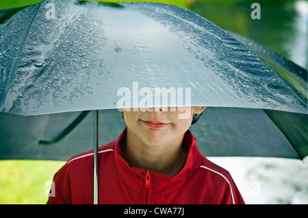 Junge unter einem Regenschirm Stockfoto