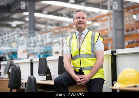 Mann, sitzend am Schreibtisch im Warehouse, Porträt Stockfoto