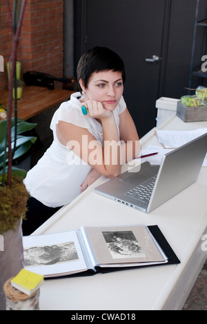 Geschäftsfrau am Schreibtisch mit Hand am Kinn Stockfoto