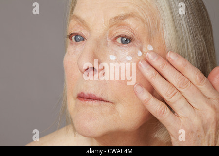 Ältere Frau Augencreme anwenden Stockfoto