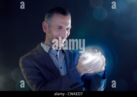 Geschäftsmann hält eine Kugel aus Licht Stockfoto