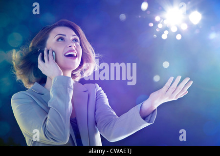 Junge Frau am Handy, blickte zu leuchten Stockfoto