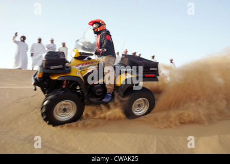 Dubai, beobachtete eine Gruppe von arabischen Männern ein Quadfahrer in der Wüste Stockfoto