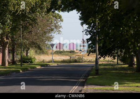 Eine verlockende Aussicht auf das Meer erblickt durch Bäume am Ende einer Allee mit Strandhütten und das Schild: "Meer" Stockfoto