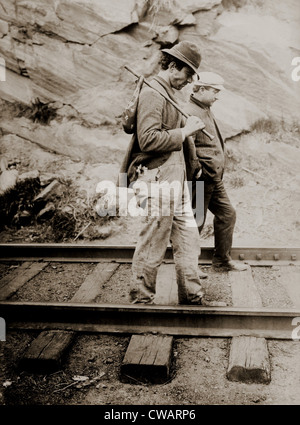 Zwei Landstreicher, verfolgt man mit einem Taschentuch gebundene Bündel auf einem Stick, zu Fuß auf dem Zug, sucht eine Gelegenheit zu hüpfen auf einem Stockfoto