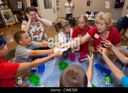 Erwachsenen ehrenamtlichen versucht, Ordnung zu halten, wie laute Kinder Wirtschaft Spiel an "Urlaub Liberty School" in der Nähe von Austin, Texas Teilnahme Stockfoto