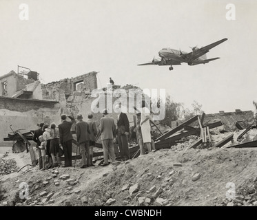 West-Berliner versammelten sich in der Nähe von Krieg-Ruinen in Berlin ein Transportflugzeug der US Air Force zu sehen. Die Berliner Luftbrücke versorgt die Stadt Stockfoto