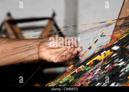 Ein Prozess der Ikat Stoff weben. Trennen die bunten Schussfäden. Stockfoto