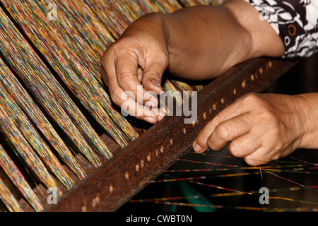 Ein Prozess der Ikat Stoff weben. Trennen die bunten Schussfäden. Stockfoto