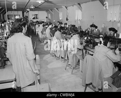 Internierte japanische Amerikaner, Sumiko Shigematsu, stehend auf der linken Seite, überwacht anderen Internierten arbeiten bei Nähmaschinen an Stockfoto