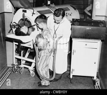 Auf dem Höhepunkt einer Polio-Epidemie, Dr. Harry Seanor, befestigt die Lunge ein Pfund auf ein acht Jahre alter Junge, zeigen die Stockfoto