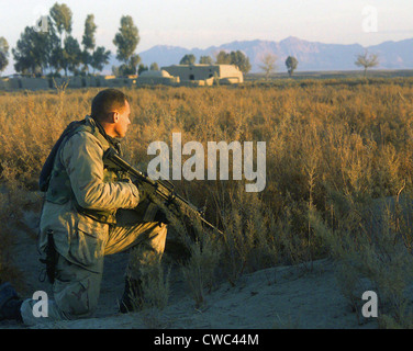 Marine Scout mit M4 Karabiner-Gewehr bewaffnet sorgt für Sicherheit an einem Straßenrand südlich von Kandahar Stadt während einer Patrouille. Kandahar ist Stockfoto