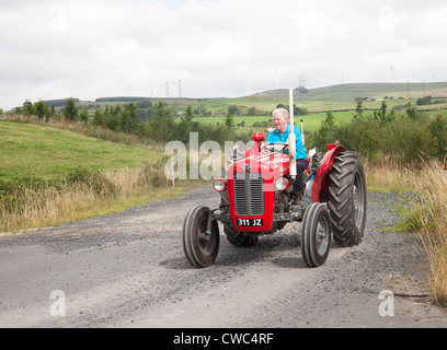 Enthusiasten, die einen rote Oldtimer-Traktor Massey Ferguson 35 X fahren, während ein Ayrshire Oldtimer Traktor und Maschine Club Straße laufen Stockfoto