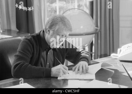 Präsident Jimmy Carter an seinem Schreibtisch im Weißen Haus Oval Office arbeiten. Ca. 1977-1980. Stockfoto