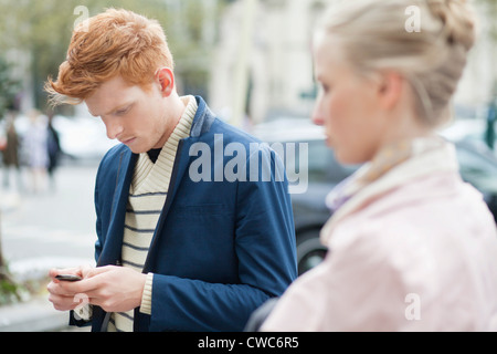 Mann von SMS-Nachrichten auf dem Handy mit ihrer Freundin neben ihn Stockfoto