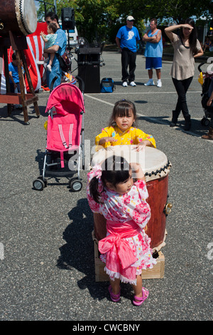 Mädchen versuchen, die Taiko-Trommeln bei einem Obon Sommerfestival in Edgewater, NJ Stockfoto