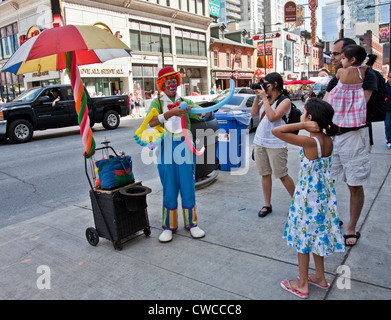 Ballon-Clown ist ein kleines Mädchen mit ihren Eltern an der Yonge Street in Toronto, Ontario unterhaltsam; Kanada Stockfoto