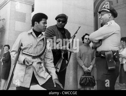 Zwei bewaffnete Black Panthers, mit einer Schrotflinte und ein halbautomatisches Gewehr, im Gespräch mit Offizier Lt. Ernest Holloway auf dem Stand Stockfoto