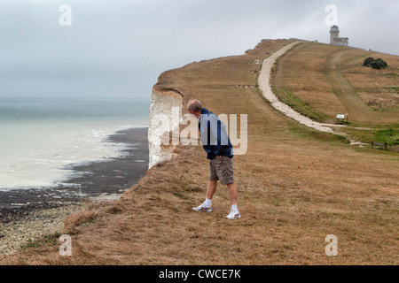 Rentner guckt nervös über den Rand des höchsten Kreidefelsen in England bei Beachy Head Stockfoto