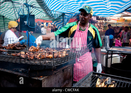 Mann, Kochen und Kochen Jerk Hähnchen auf Brixton Street Party zu verkaufen Stockfoto