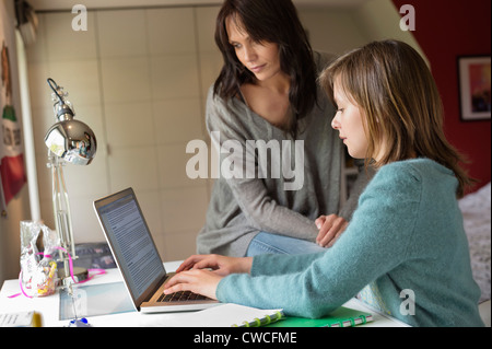 Mädchen mit ihrer Mutter auf einem Laptop zu Hause studieren Stockfoto