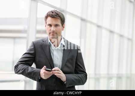 Porträt einer Geschäftsfrau Textnachrichten auf dem Handy in einem Büro Stockfoto