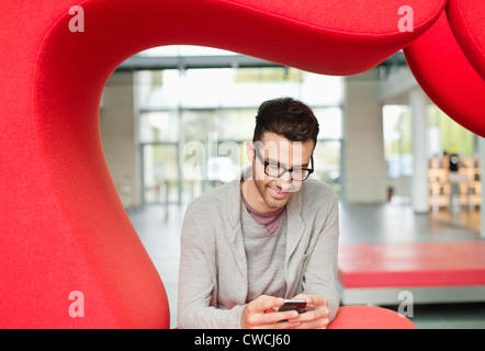 Geschäftsmann Text-messaging und lächelnd in einem Büro Stockfoto