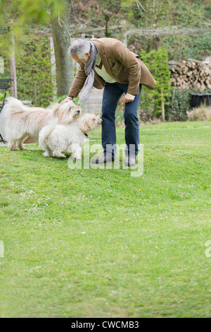 Mann spielt mit seinen Haustieren in einem Garten Stockfoto
