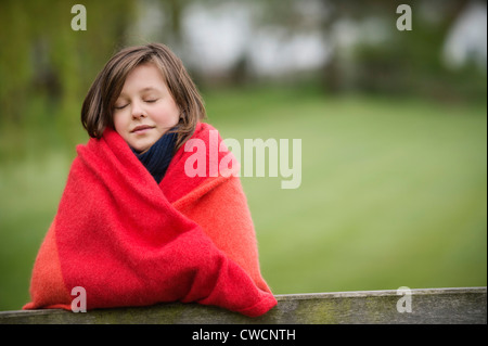 Mädchen, eingewickelt in eine Decke mit ihren Augen geschlossen in einer farm Stockfoto