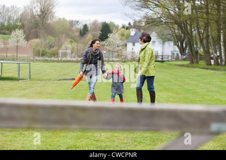 Mädchen gehen mit ihrer Mutter und Großmutter in einem Rasen Stockfoto