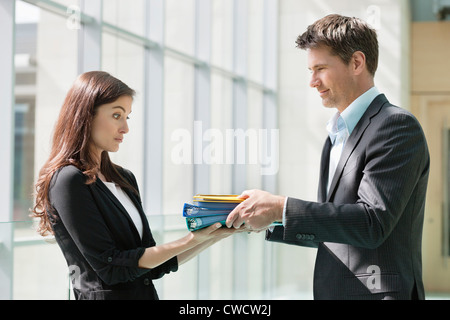 Geschäftsleute, die seine Kollegin in einem Büro Dateien erteilen Stockfoto