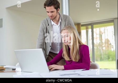 Mann sucht eine Frau auf einem Laptop arbeiten Stockfoto