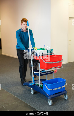 Männlichen Reiniger drängen Trolley mit Reinigungsanlagen Stockfoto