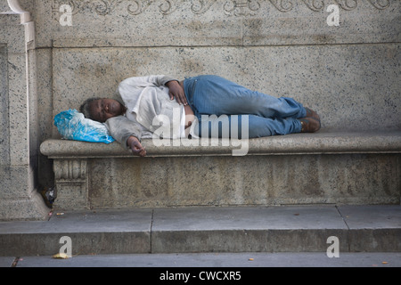 Obdachlose Frau ruht auf einer Bank an der Außenseite der New York Public Library in 42nd St. & 5th Avenue in New York City. Stockfoto