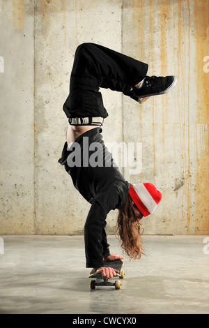 Junger Mann macht Handstand auf Skateboard Stockfoto