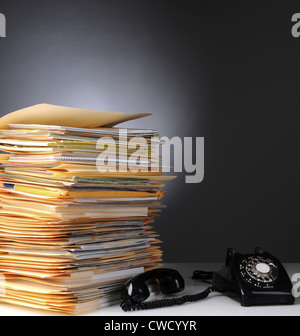 Einen großen Stapel von Dateien auf einem Schreibtisch und einem Telefon Retro-Stil mit dem Empfänger aus dem Schneider. Stockfoto