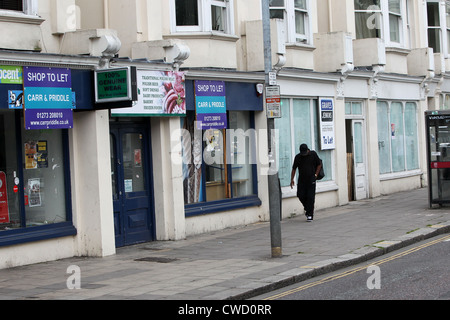 Ein Mann im Bild, vorbei an leerstehenden Läden in Brighton, East Sussex, UK. Stockfoto