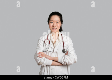 Porträt eines asiatischen weiblichen Arzt Stand mit verschränkten über grauen Hintergrund Stockfoto