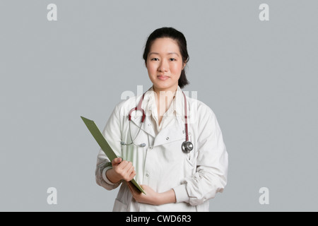 Porträt eines asiatischen weiblichen Arzt hält eine Zwischenablage über grauen Hintergrund Stockfoto