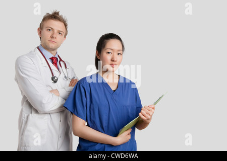 Porträt eines kaukasischen Arztes stehend mit einer asiatische Krankenschwester über grauen Hintergrund Stockfoto