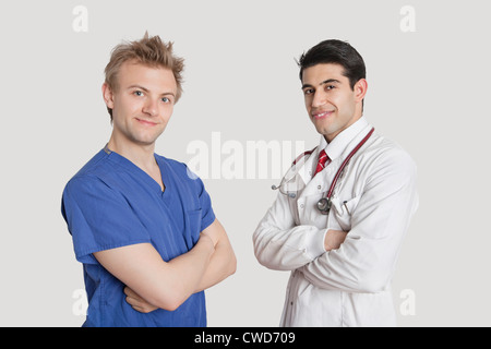 Porträt von glücklich männliche Krankenschwester und Arzt Stand mit verschränkten über grauen Hintergrund Stockfoto