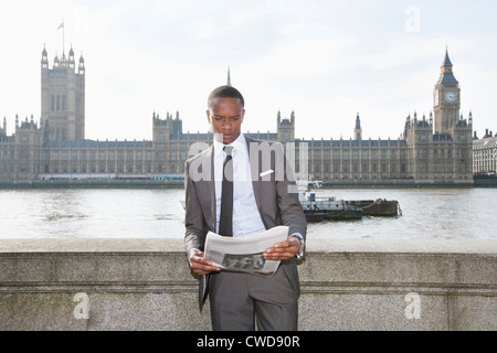 Afrikanische amerikanische Geschäftsmann Zeitunglesen mit Gebäude im Hintergrund Stockfoto