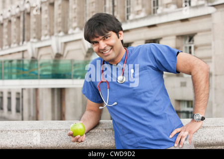 Porträt eines indischen männlichen Arzt hält einen grünen Apfel Stockfoto