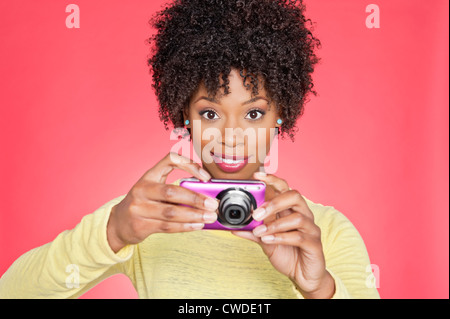 Porträt einer afroamerikanischen Frau hält eine Kamera über farbigen Hintergrund Stockfoto