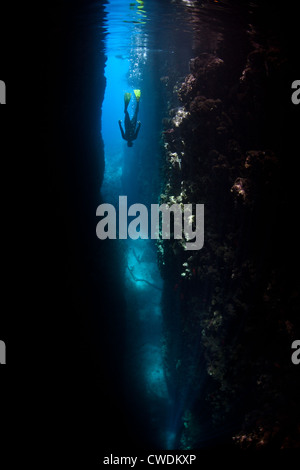 Ein Freediver hinab in einen tiefen Spalt, der in einer Kalksteininsel einschneidet. Florida Inseln, Salomonen, Pazifik. Stockfoto