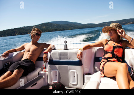 Zwei glückliche junge Erwachsene Lachen und reden auf der Rückseite des Wakeboard-Boot an einem sonnigen Tag in Idaho. Stockfoto