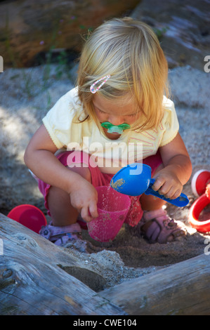 Kind blondes Mädchen Baby mit Sand im Sandkasten spielen Stockfoto