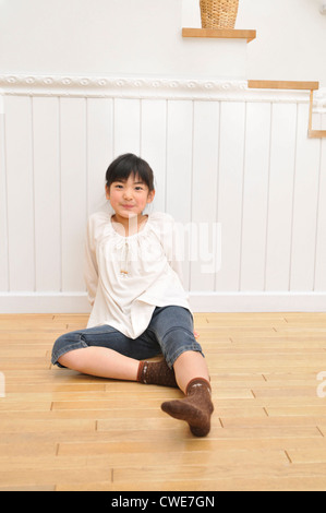 Mädchen sitzen auf Holzboden Stockfoto