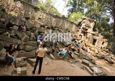 Horizontale Ansicht von Touristen sitzen auf führen die Ruinen einer Wand mit einer Tour in Ta Prohm oder Tomb Raider-Tempel in Angkor Thom. Stockfoto