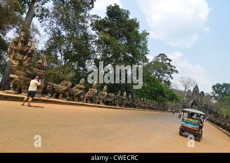 Horizontale Ansicht von Touristen, die die Fotos von den Statuen der Götter und Dämonen führt zu das Siegestor in Angkor Thom, Kambodscha Stockfoto